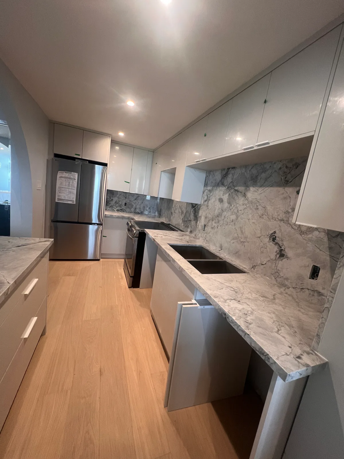 Completed white kitchen with marble-look counter and backsplash at 3000 Bathurst
