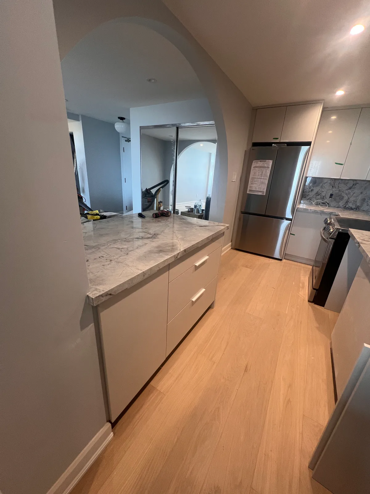 Completed kitchen and living-room sightline through an arch at 3000 Bathurst