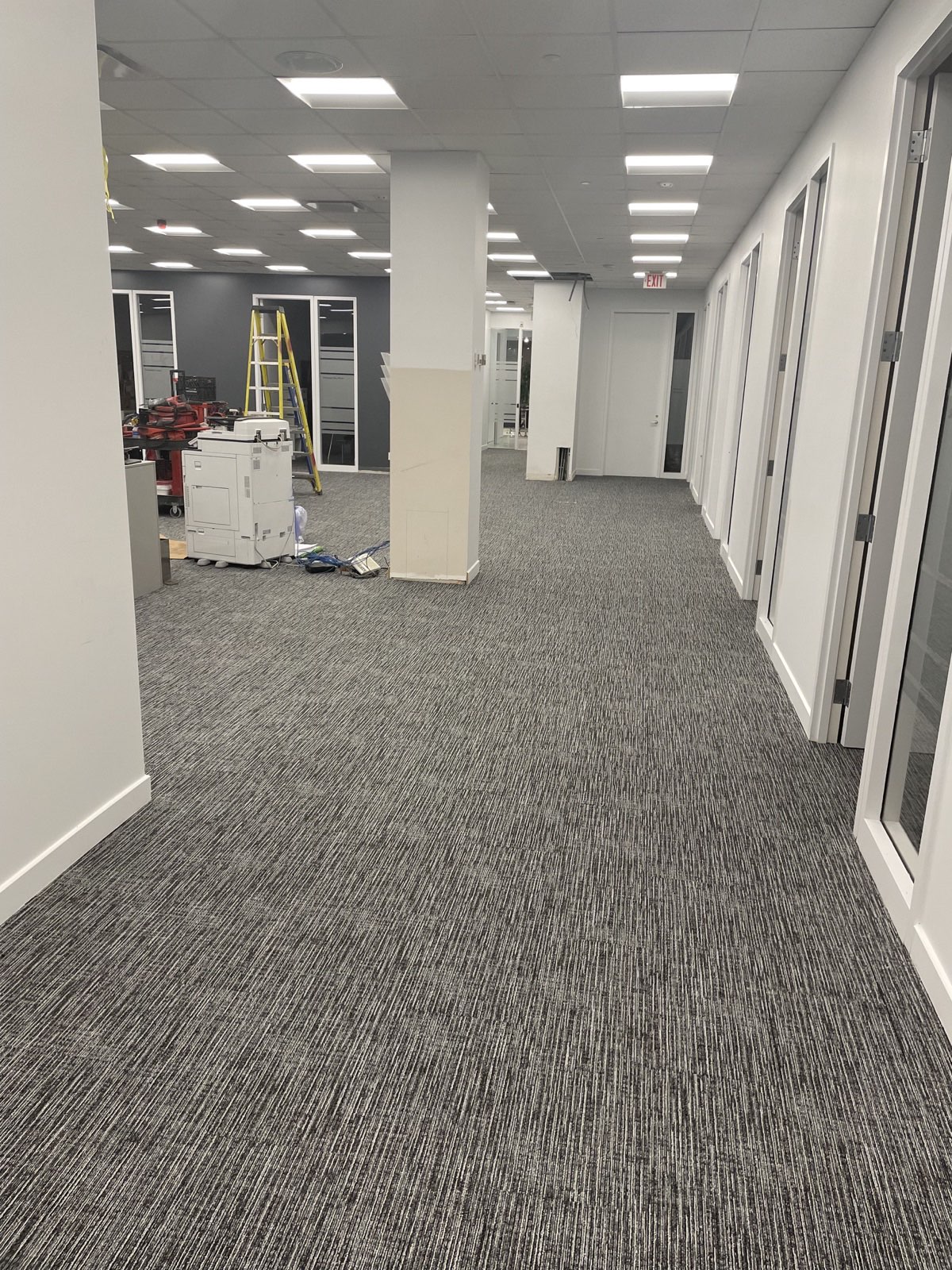 Commercial office common area with grey carpet tile during active fit-out work