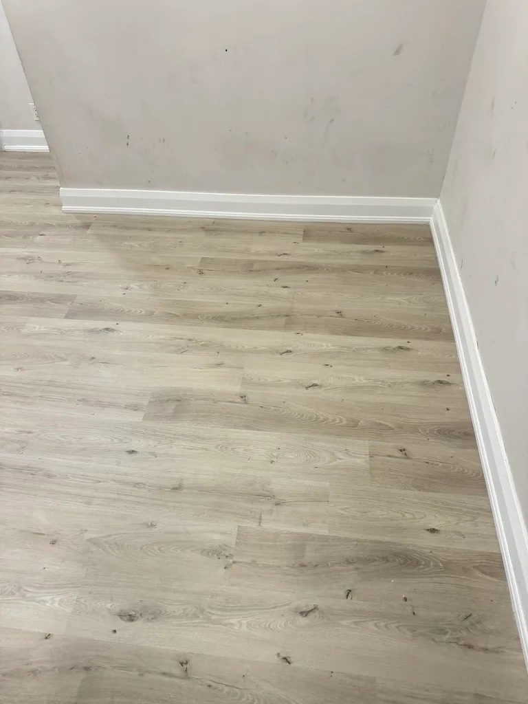Finished light plank floor and white baseboard at the Toronto project