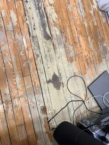 Worn strip flooring and patched floor section before replacement on Eglinton Avenue West, Toronto