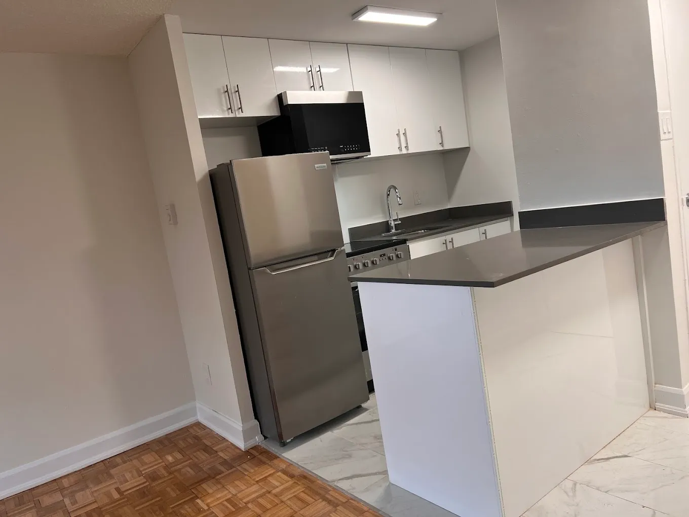Completed kitchen with white cabinetry, dark counters, and island