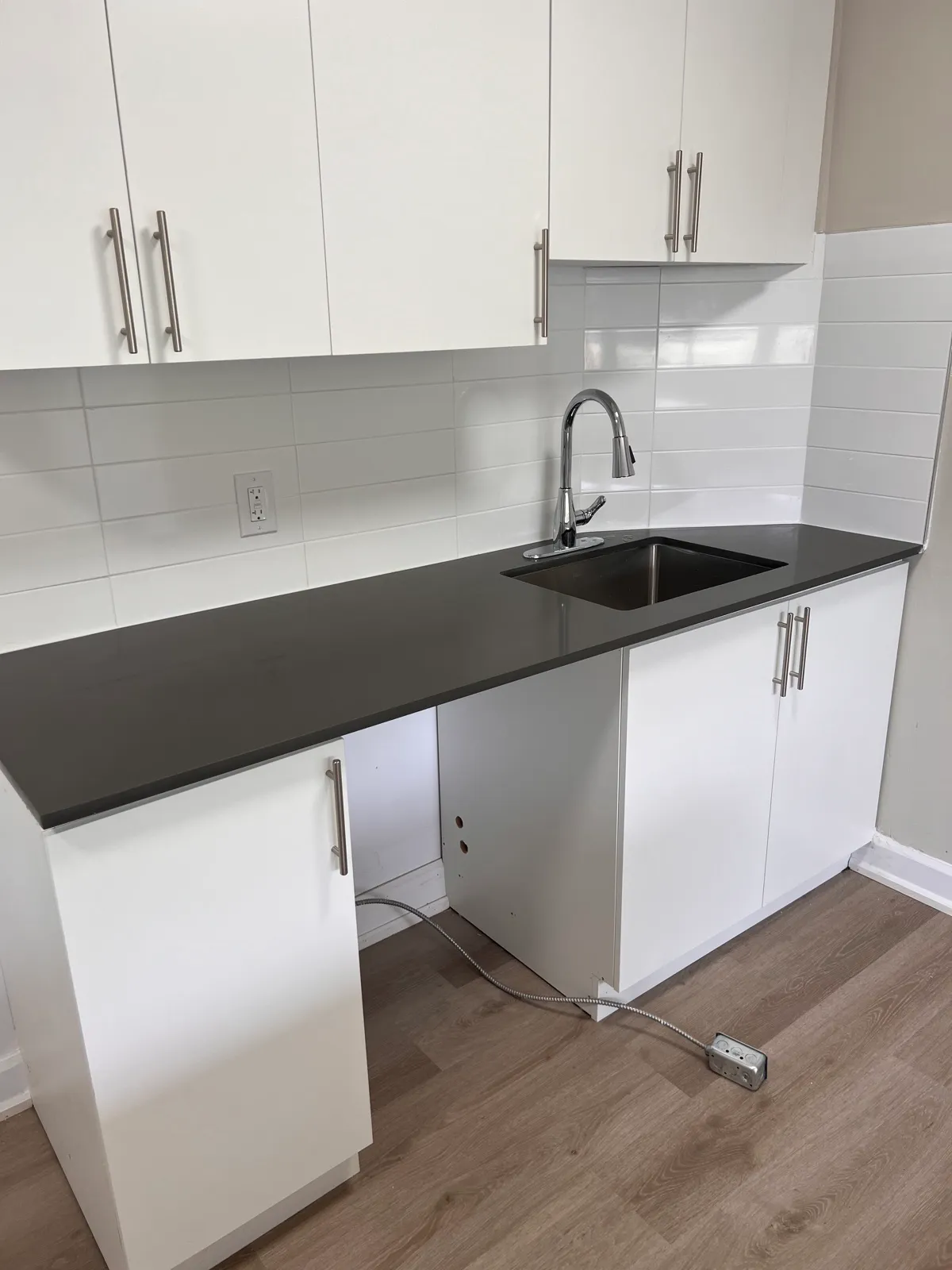 Kitchen sink, dark counter, and white tile backsplash