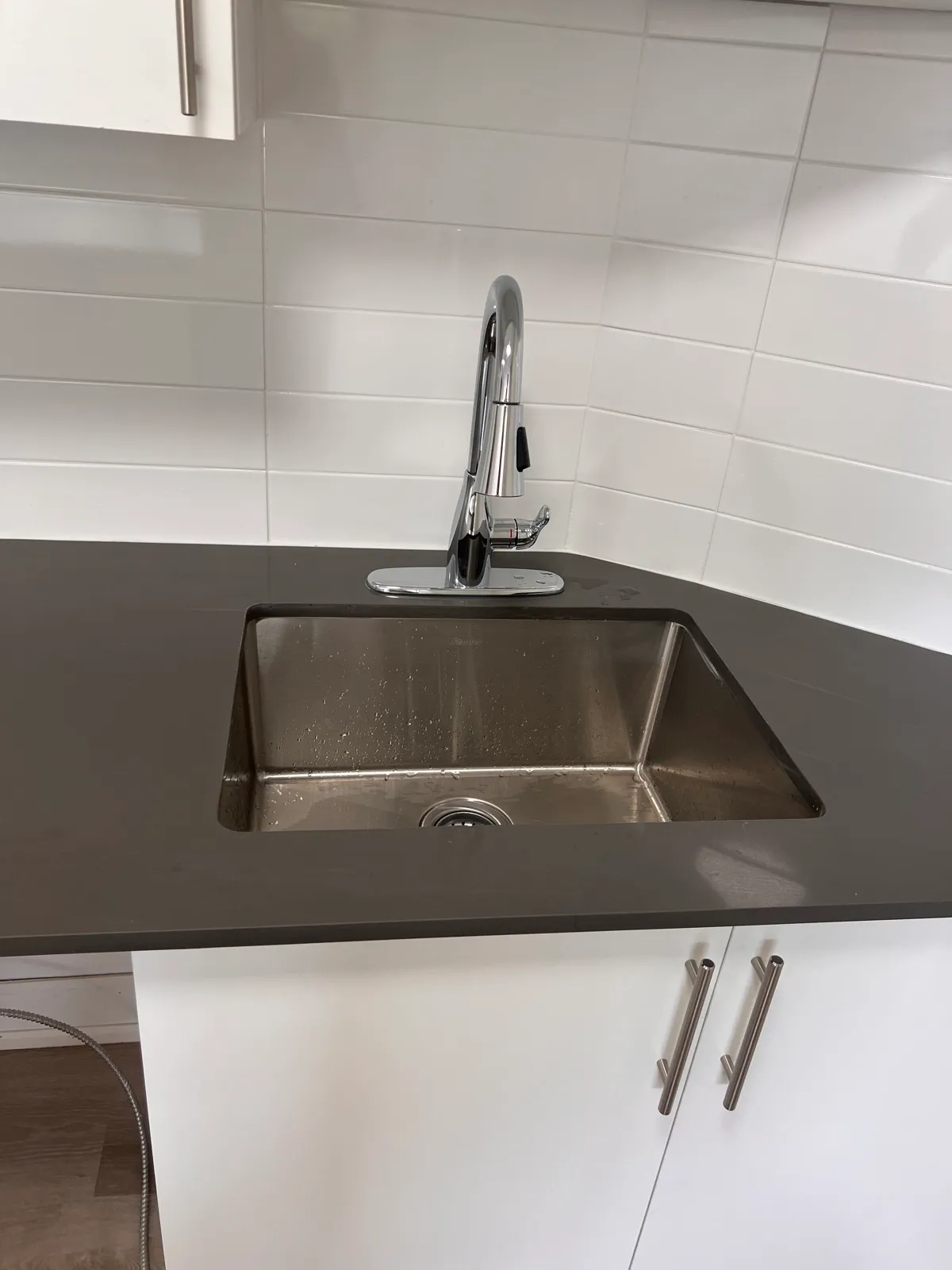 Finished kitchen faucet, counter, and white tile backsplash
