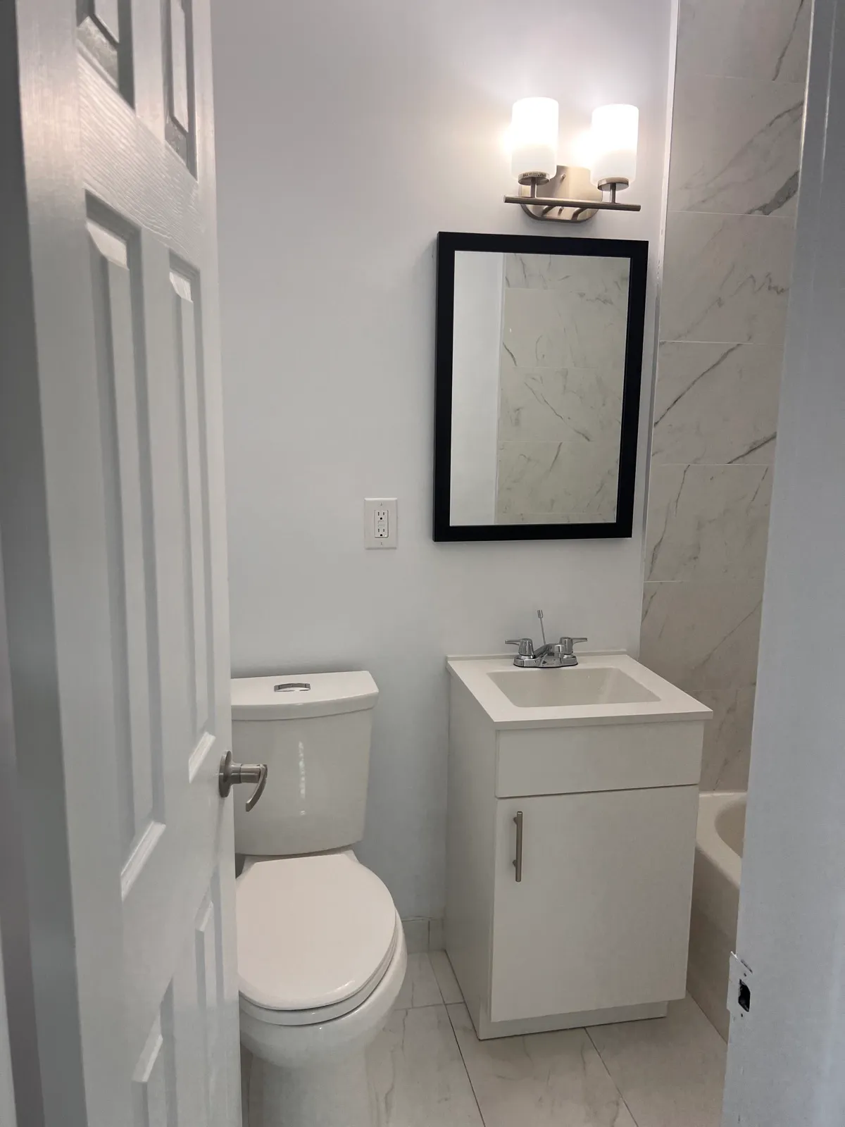 Finished bathroom vanity, mirror, and marble-look wall tile