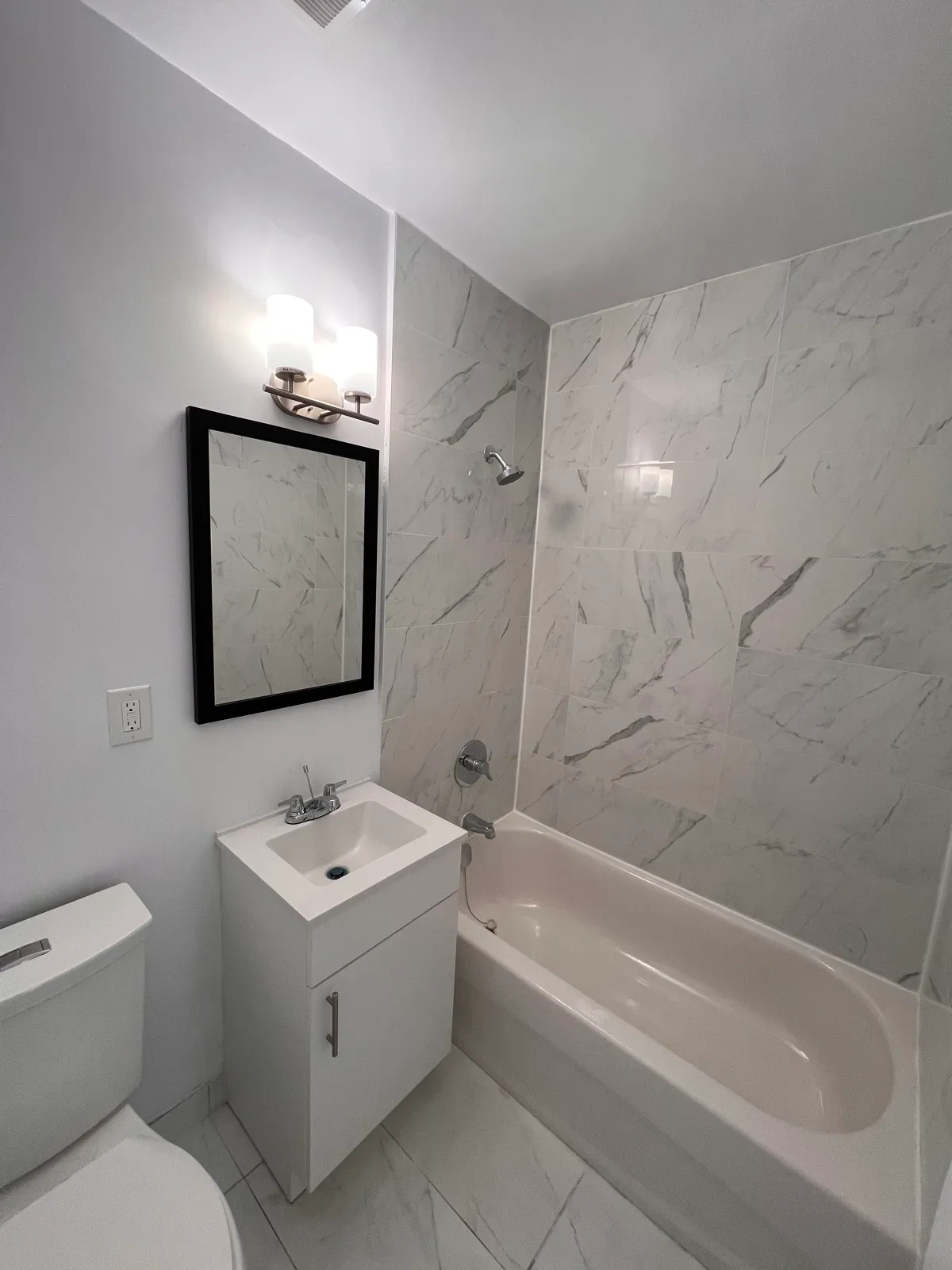 Completed bathroom with tiled tub surround and vanity