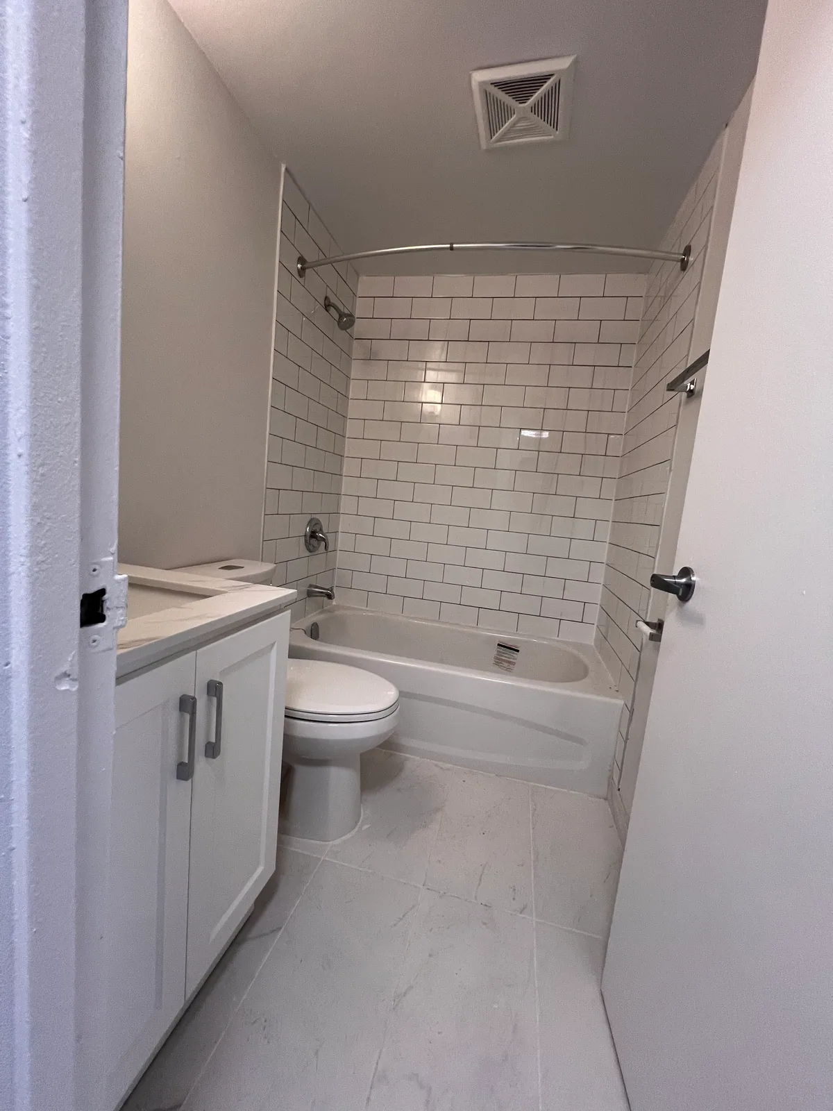 Doorway view of completed Goreway condo bathroom with white vanity