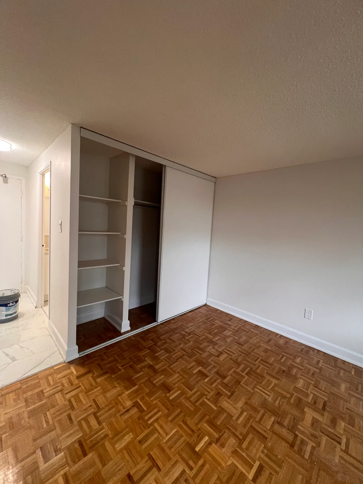 Wide view of finished closet and refreshed parquet floor in Brampton condo