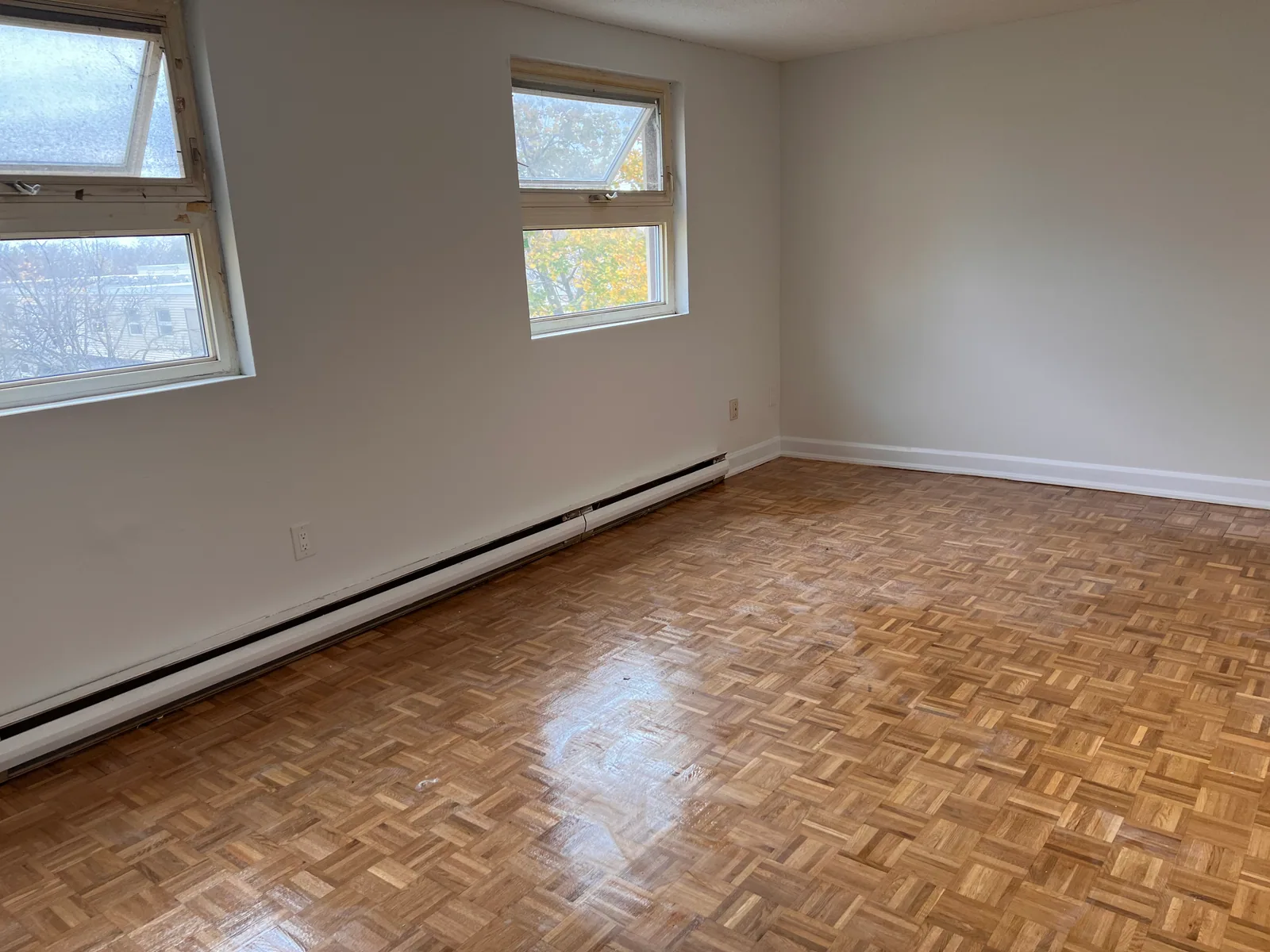 Finished living area with parquet floor, white trim, and two windows