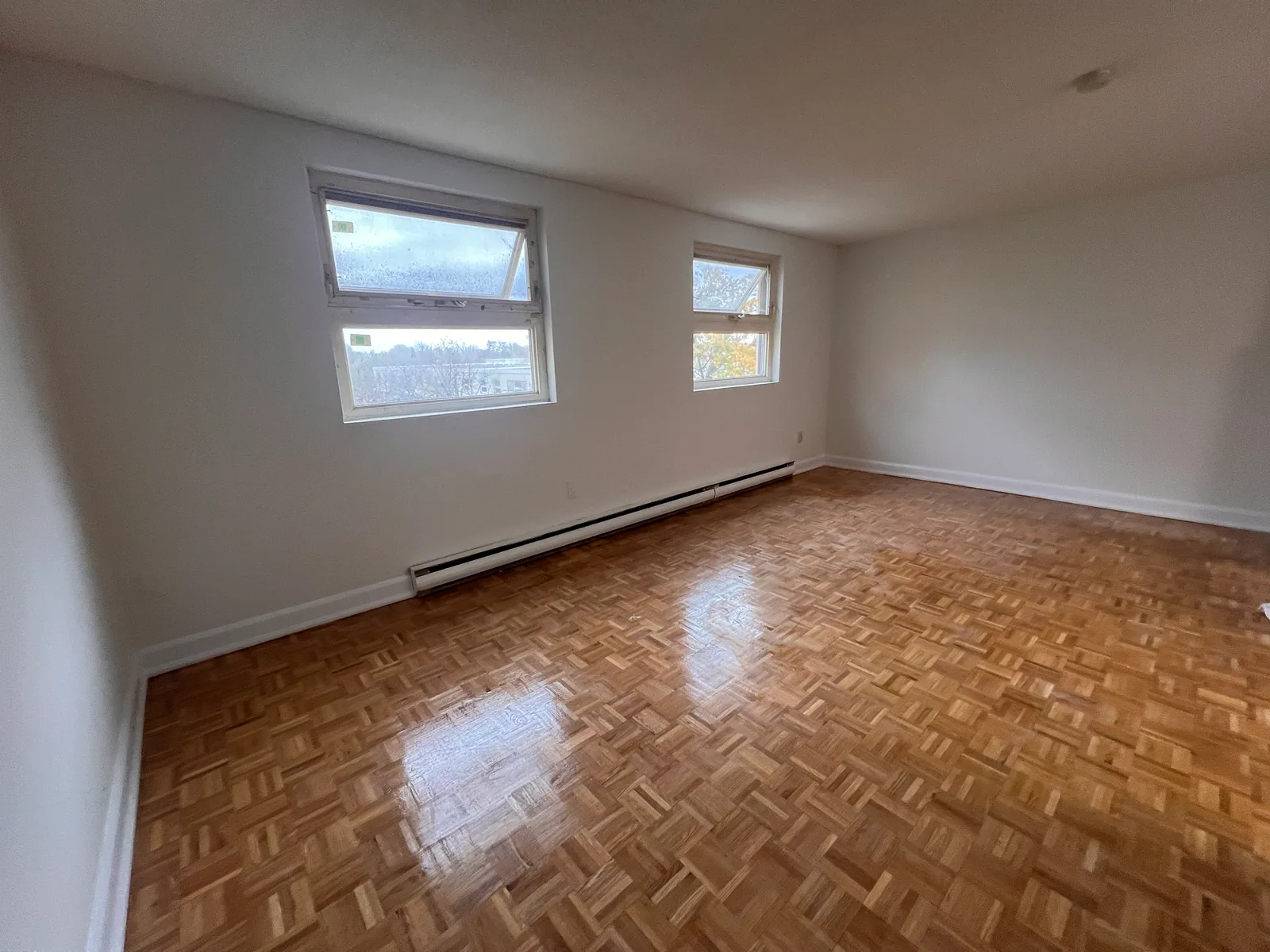 Wide completed living room view with refreshed parquet and baseboard heater