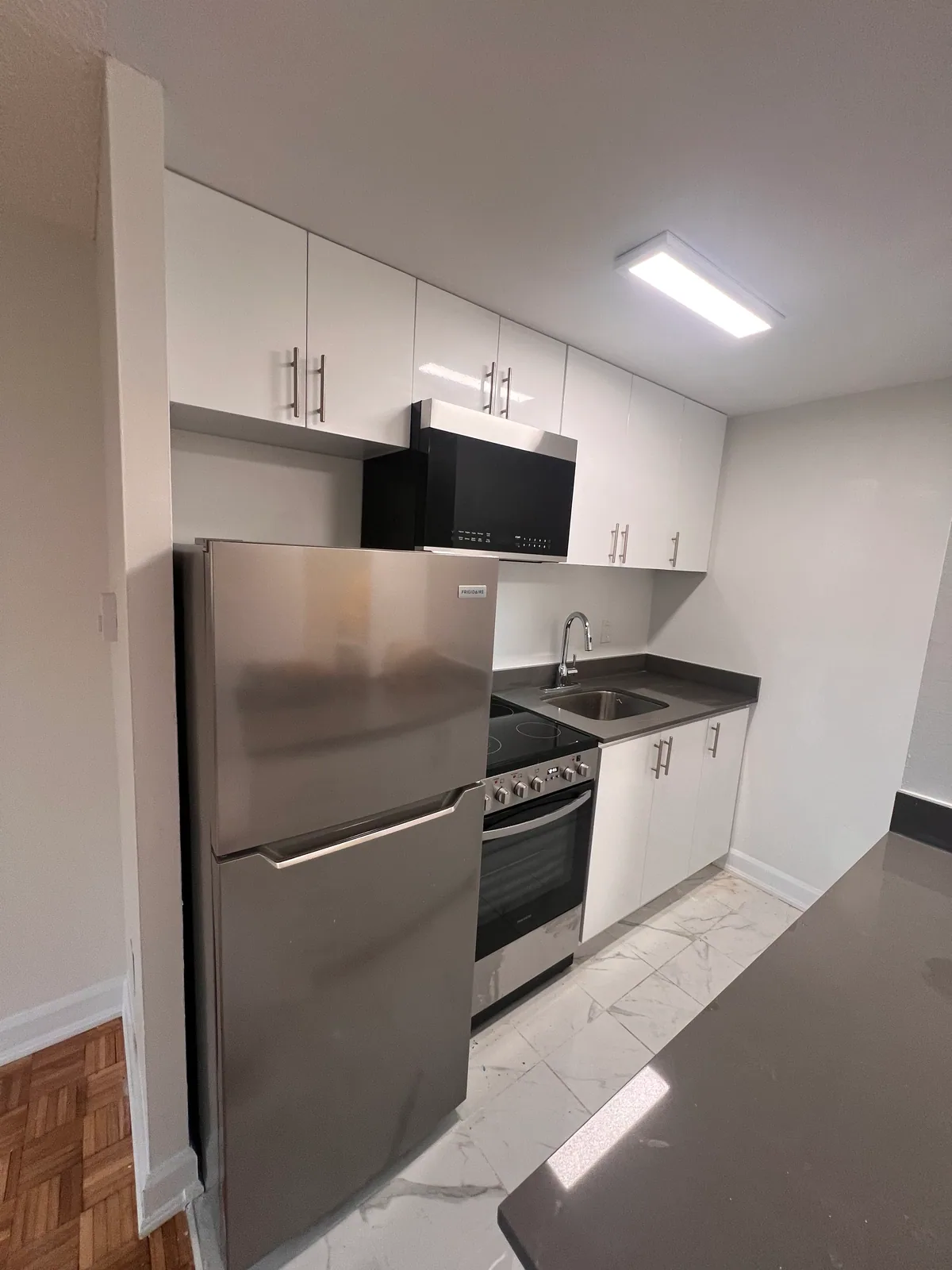 Completed compact kitchen with refrigerator, range, sink, and grey countertop