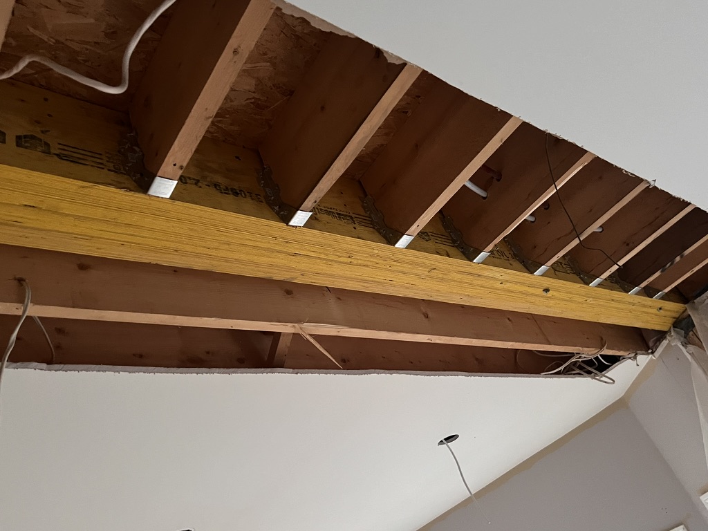 Exposed ceiling framing and wood beam above a wall opening