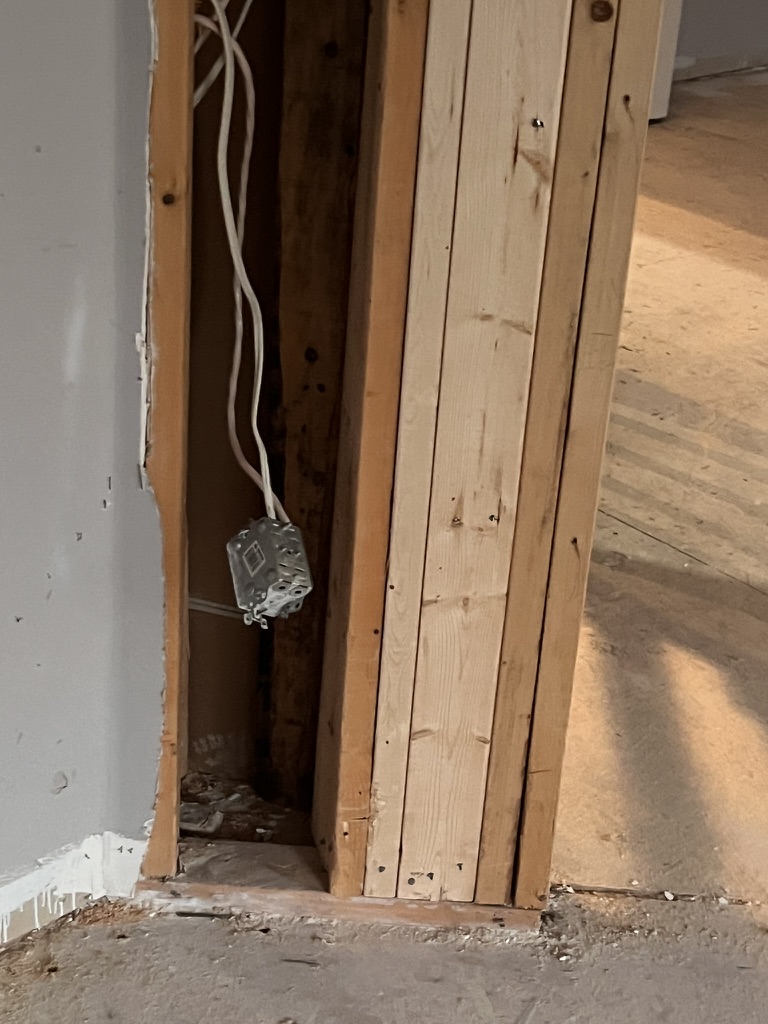 Stud framing and an electrical box exposed beside an opening