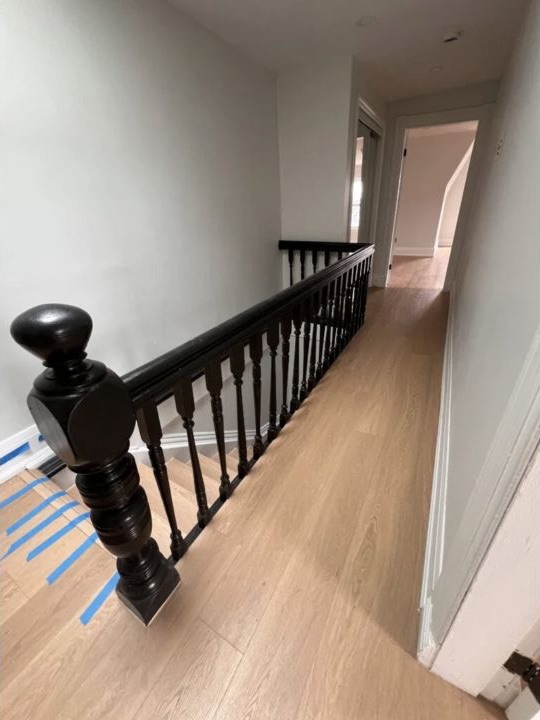 Upper hallway with refinished black stair railing and light wood flooring