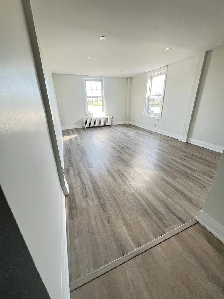 Bright finished room with new plank flooring, white walls, trim, and natural light
