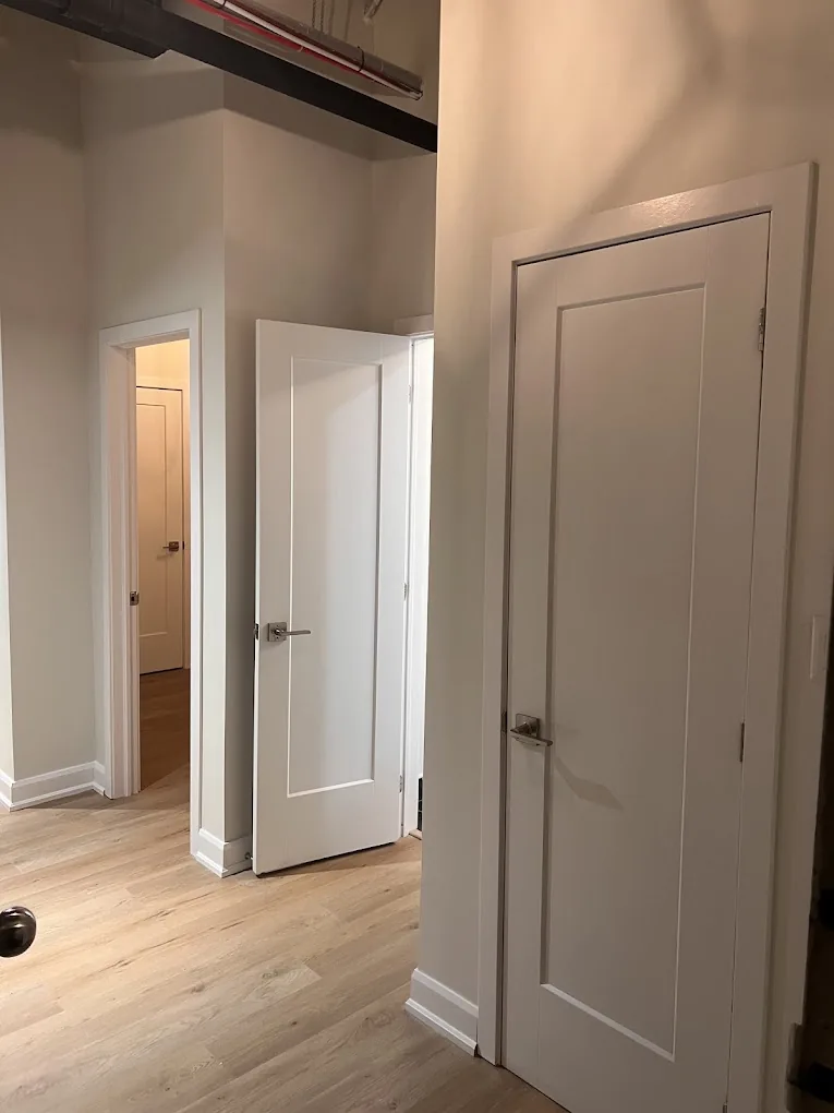 Finished interior corridor with white doors, trim, and warm wood flooring